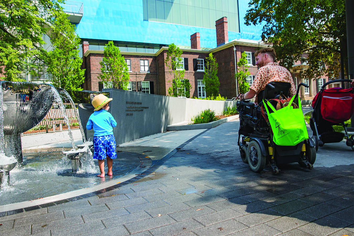 Anderson says hi to a young boy playing in a fountain as he wheels by on a paved path.