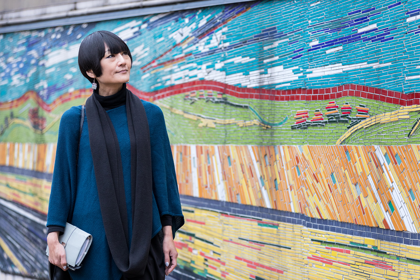 Aiko Ito walks by a mosaic on the side of a building