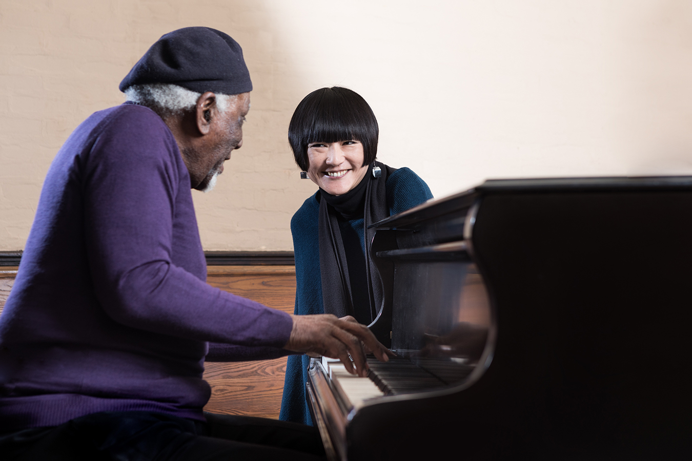 Aiko Ito listening to man in purple sweater play piano