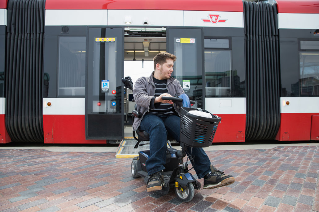 Image of a man riding a mobility scooter in front of a streetcar
