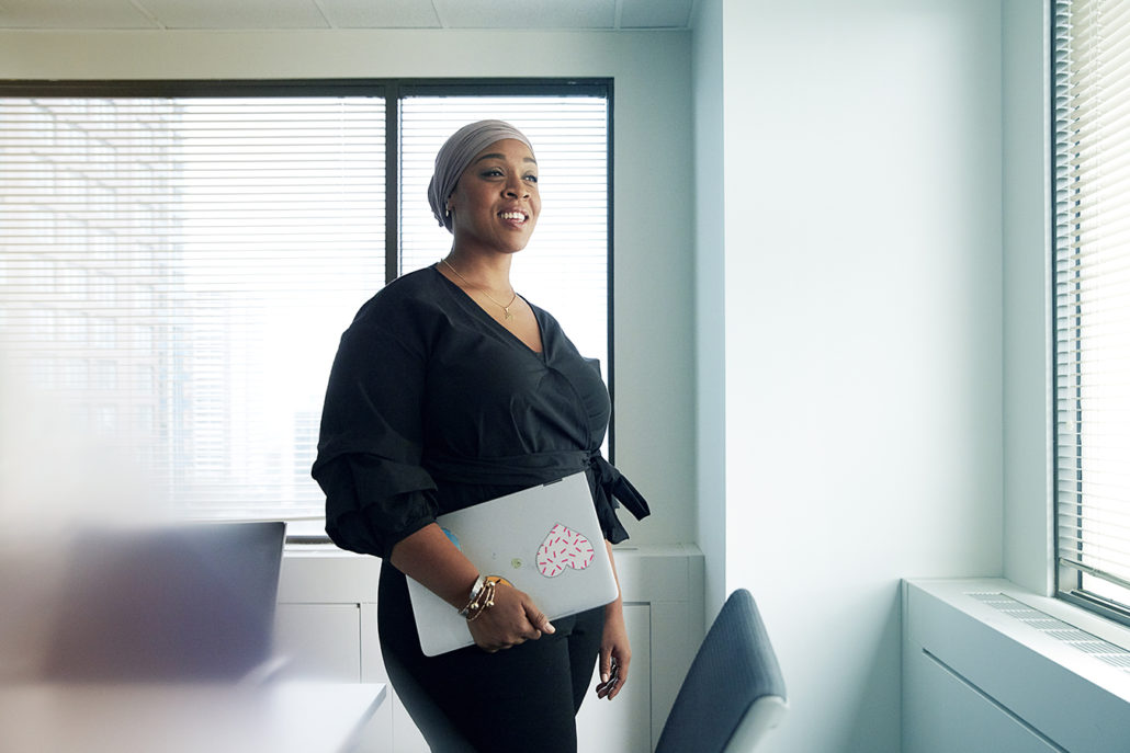 Dr. Fatimah Jackson-Best stands in a conference room holding a laptop