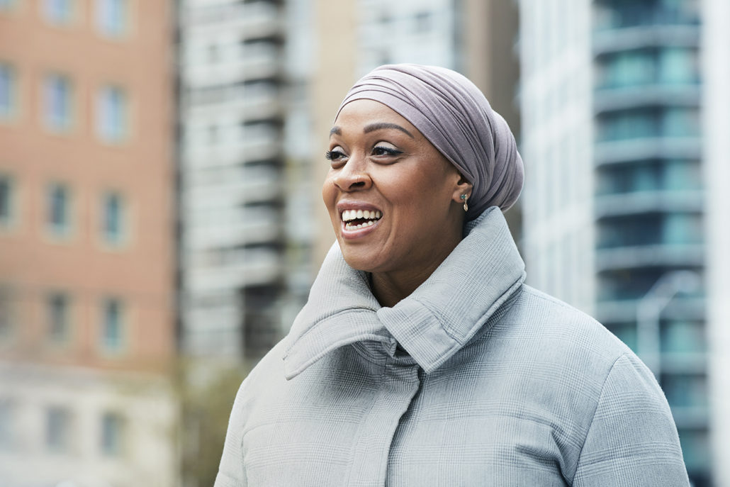 Dr. Fatimah Jackson-Best stands outside in front of a high rise building smiling. 