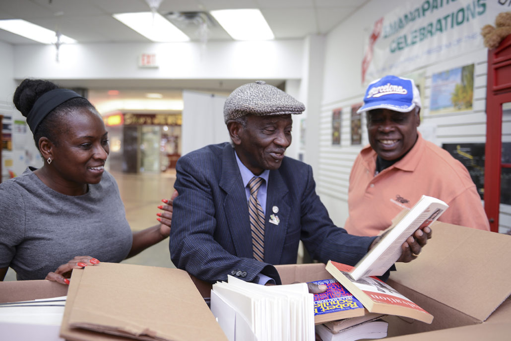 Image of Winston LaRose looking at books and speaking to two people