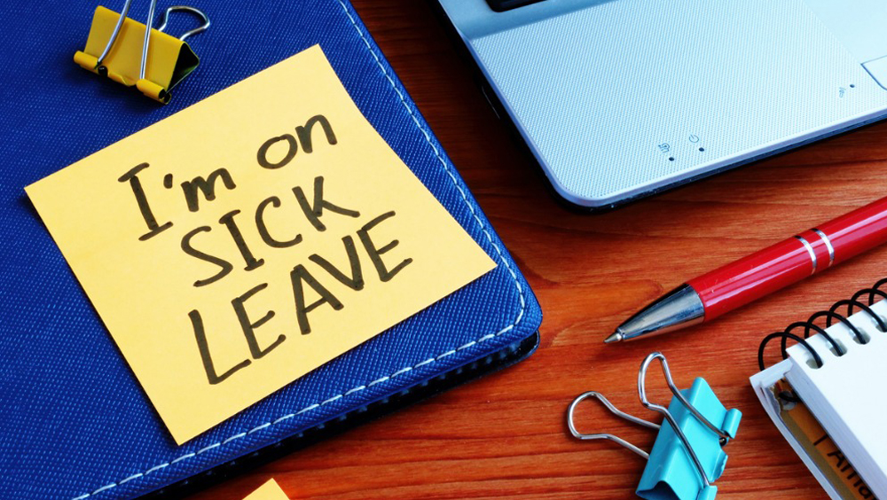 A sticky note "I'm on sick leave" on desk.