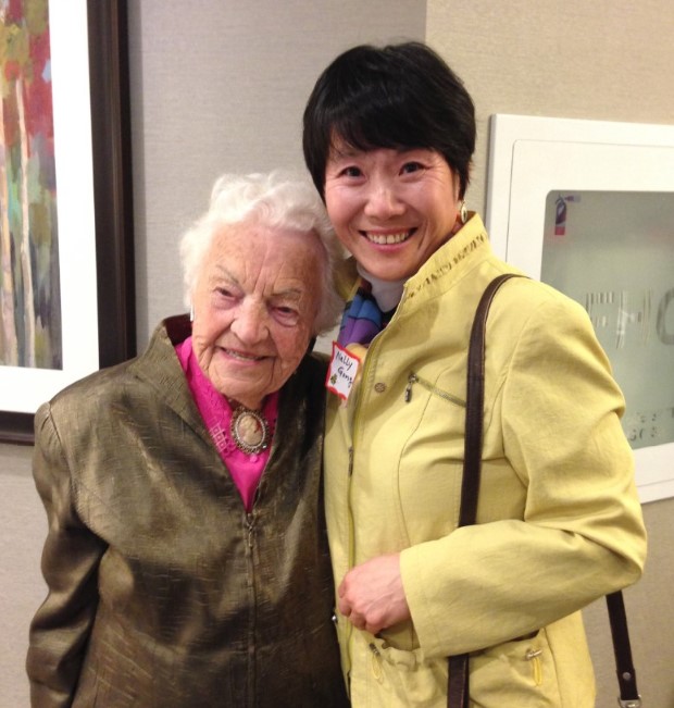 Nelly Gong stands with a senior at a community event. 