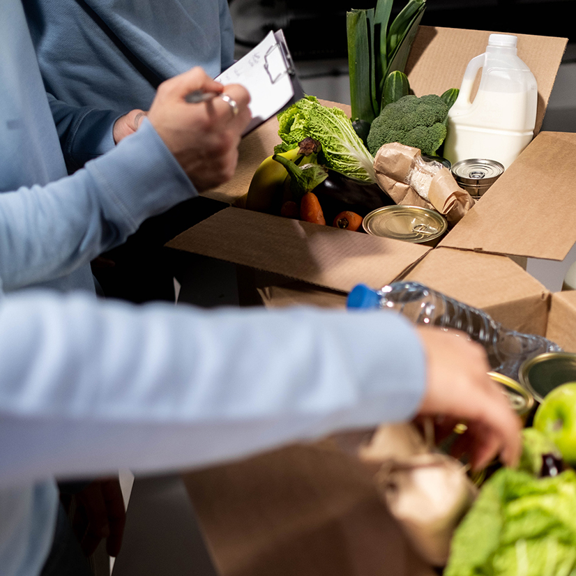 Volunteers putting food in donation box.