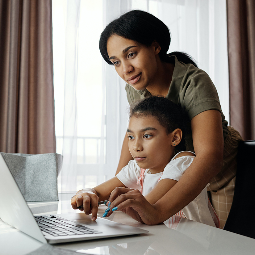 Mom helping daughter on Laptop.