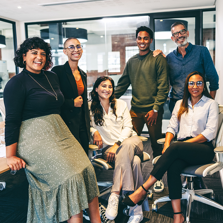 Group of happy businesspeople smiling at the camera in a boardroom.