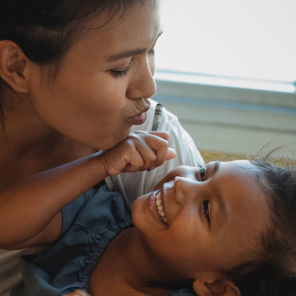 A mother holding and kissing her child