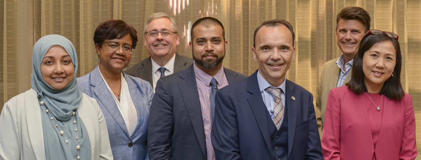 Group of diverse board members stand side-by-side and smile at the camera.