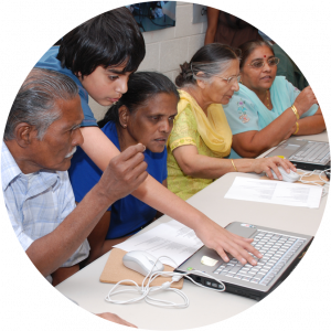 A young boy helping seniors during computer classes