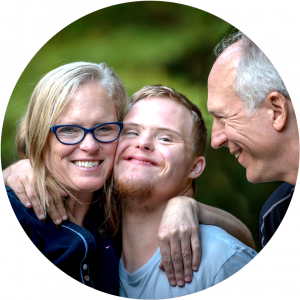 A loving family of three, son with down syndrome is hugged by his mother in the park