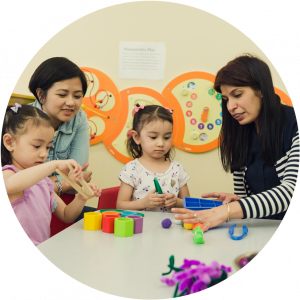 A mom and her two children with a teacher playing with colorful toys at Early Year Center