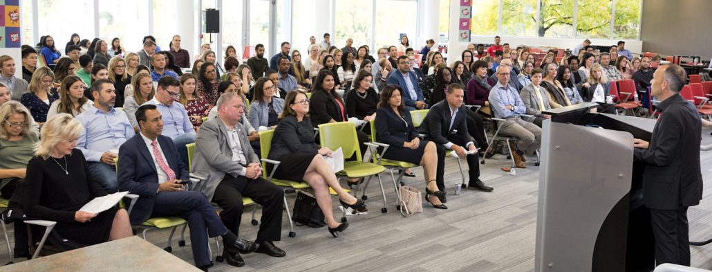 Shot of CEO delivering a speech to a large crowd during a event.