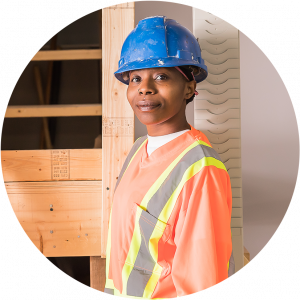 Young smiling female worker in workwear and protective helmet standing in workshop