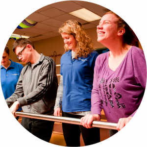 Two physician in uniform helping two patients with physical disabilities improving their mobility by using studio equipments