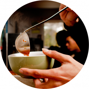 A hand scooping soup into a small bowl