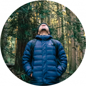 A man in woods looking up at sky