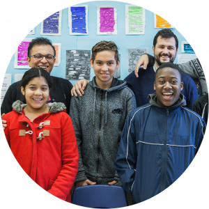 Two education workers and three children all smiling and standing together in classroom