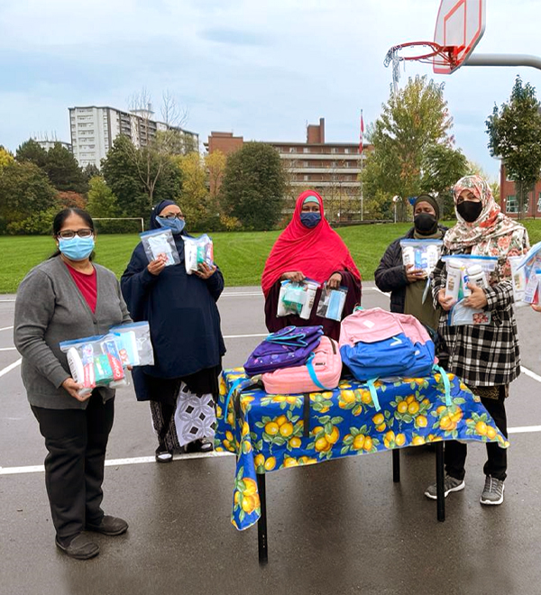A group of people wearing face mask assemble care packages and backpacks