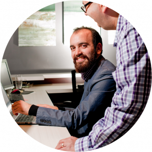 A man working on computer, a instructor standing beside him