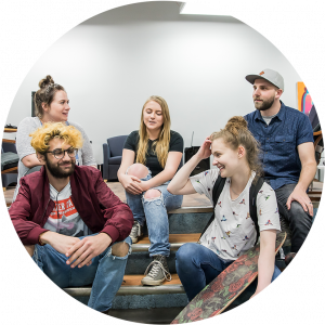 Group of teens and a program coordinator sitting together talking and laughing