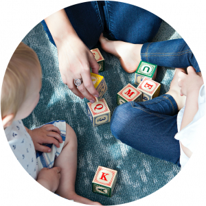 Closeup shot of a women and two children playing with alphabet blocks on floor