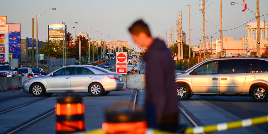 Two cars drive down a busy street in the Greater Golden Mile