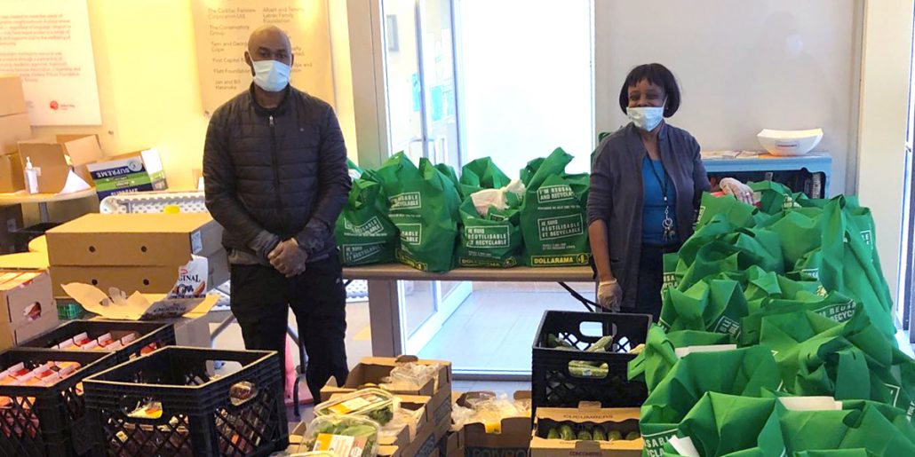 Two masked individuals show a large collection of crates for a food security initiative