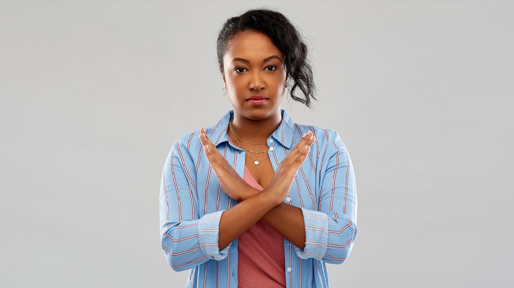 Photo of a young woman making an ‘x’ with her arms