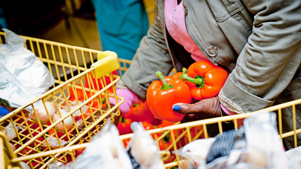 Woman at a local food bank places food in a grocery cart