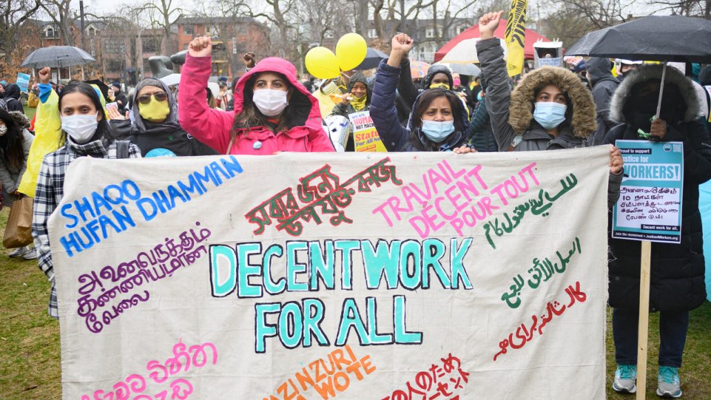Photo of four people holding up a banner reading: Decent work for all