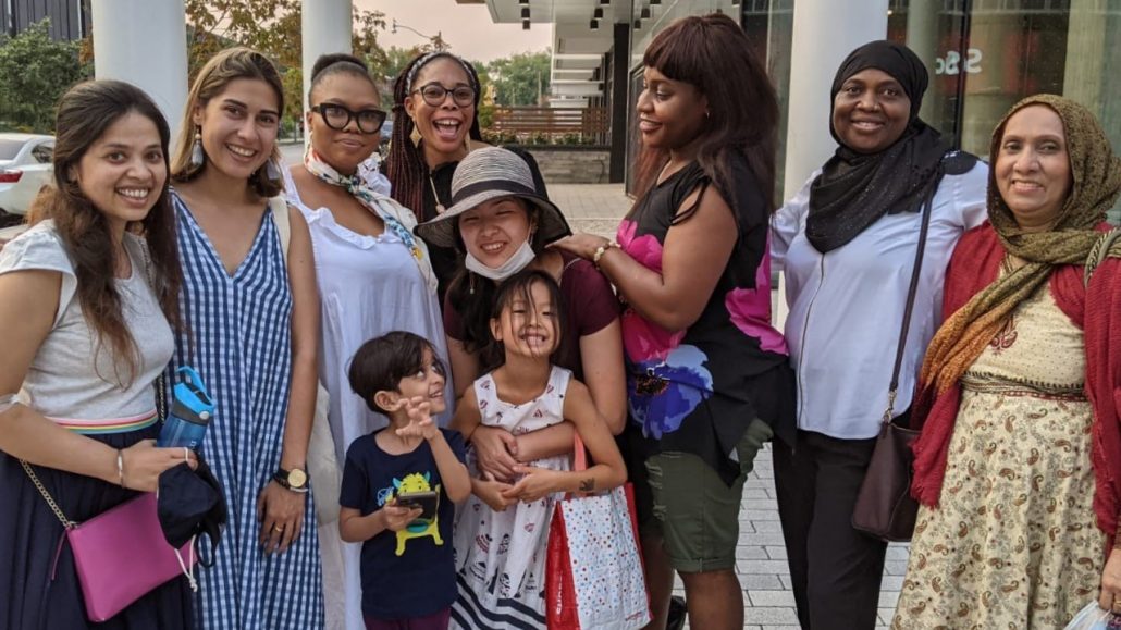 Photo of a group of people and two children dressed in summer clothing posing outside.  