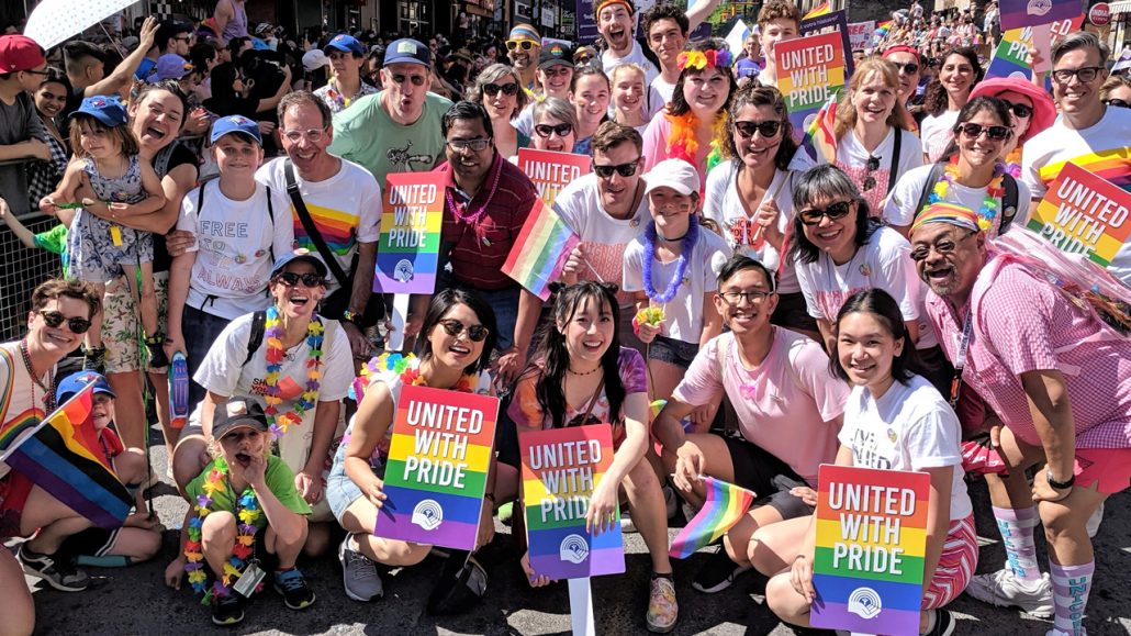 Photo of United Way employees holding “United with Pride” signs at a past Toronto Pride Parade.