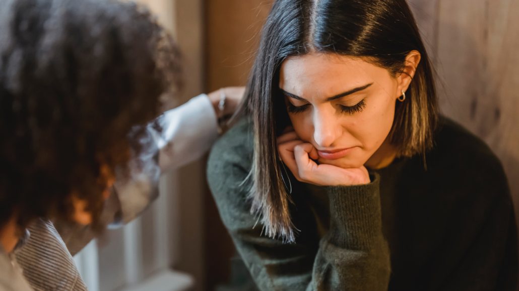 Photo of a young woman in emotional distress being comforted