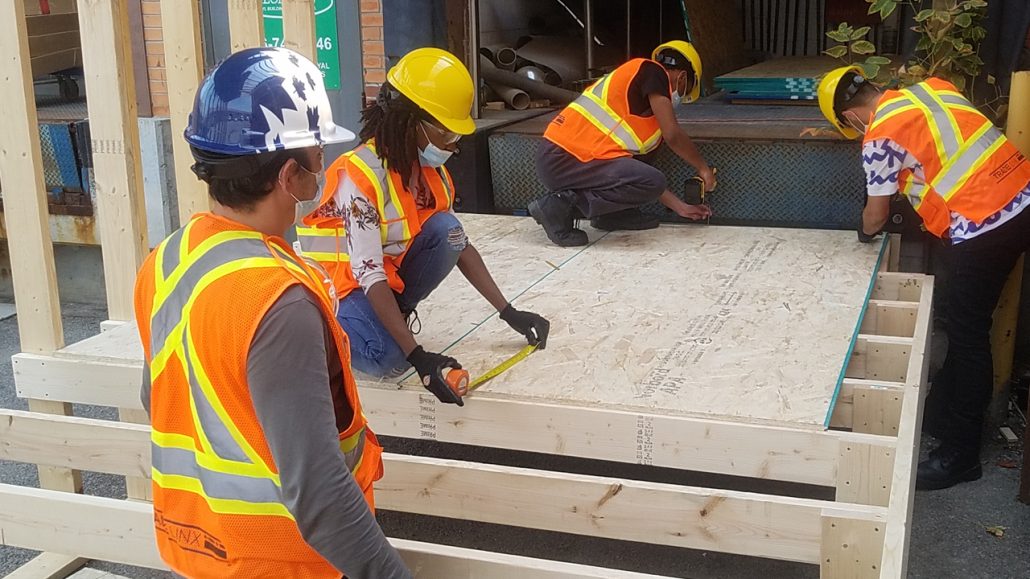 Construction workers wearing hard hats and vests working on a house