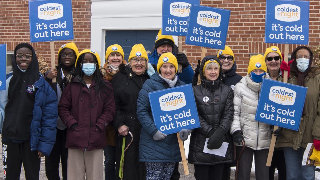 A group of people from Blue Door Shelter holding signs that read 'its cold out here'