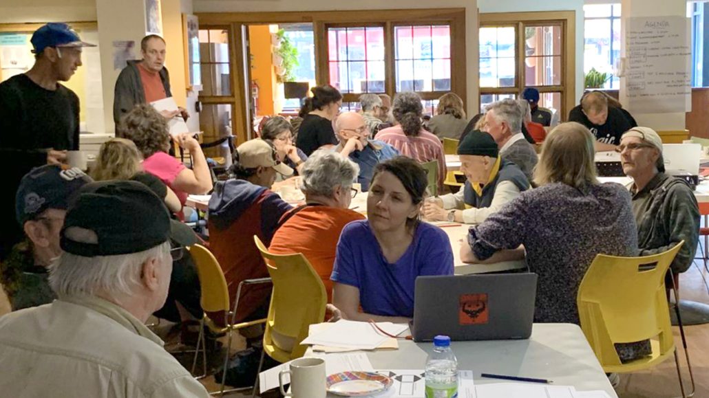 Groups of residents talk together around large tables at PARC