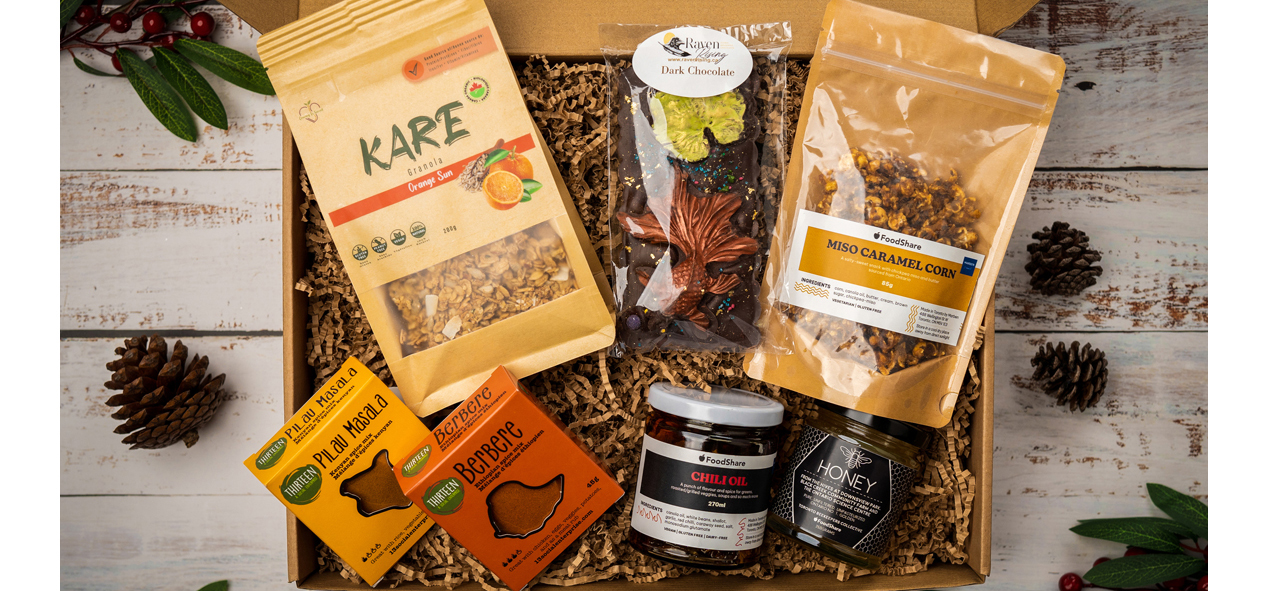 Photo of the FoodShare gift box with a chocolate bar from Raven Rising Global Indigenous Chocolates, granola from Kare Granola, spice mixes from Thirteen: A Social Enterprise, honey from the Toronto Beekeeper’s Collective, miso caramel corn, and chili crisp oil from the
FoodShare x Marben Restaurant collaboration.
