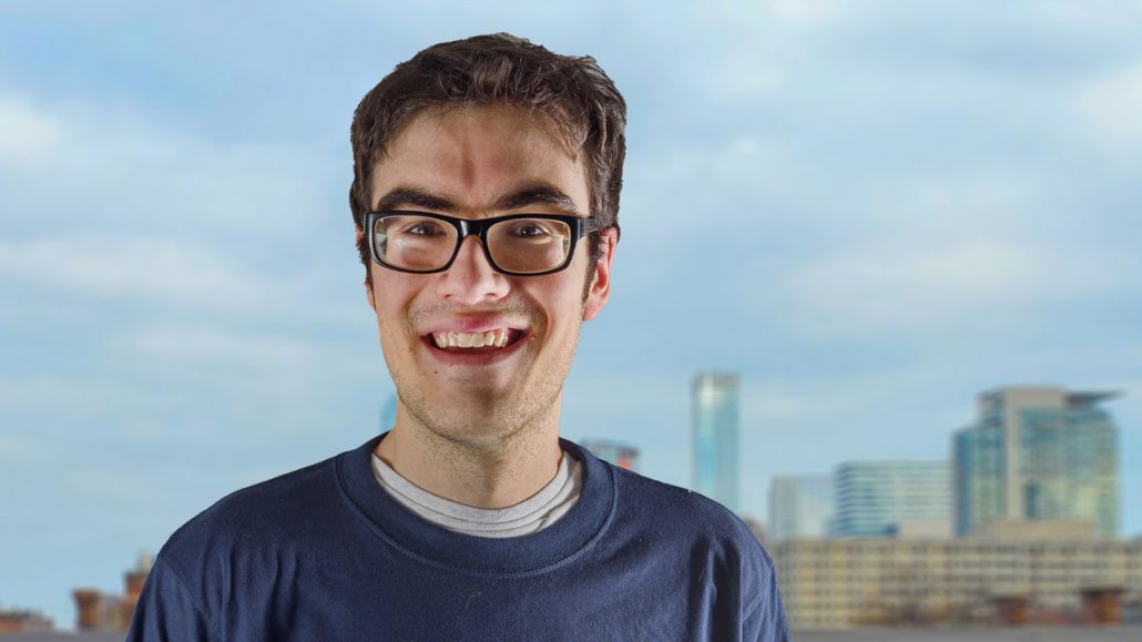 Photo of Sam posing in front of a city skyline. 