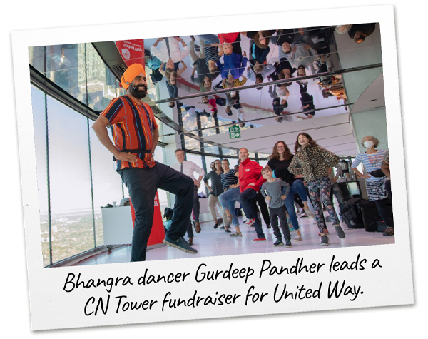 Bhangra dancer Gurdeep Pandher stands in front of a window in the CN Tower’s observation deck and leads a group of people in a dance