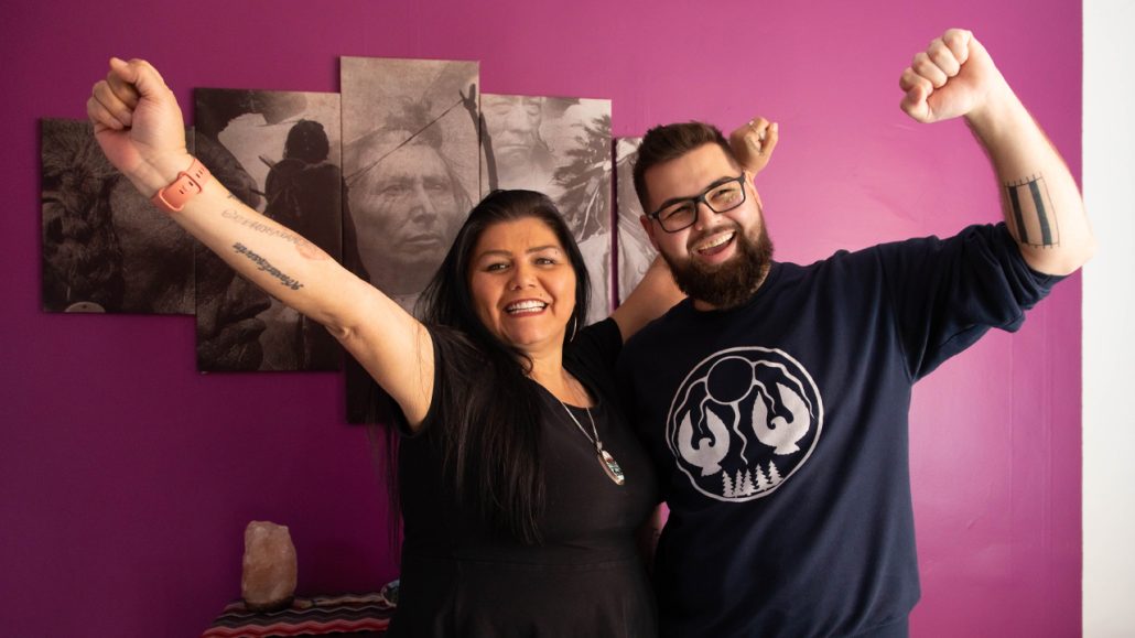 The executive director of ENAGB Indigenous Youth Agency and a youth member pose with arms outstretched in celebration. 