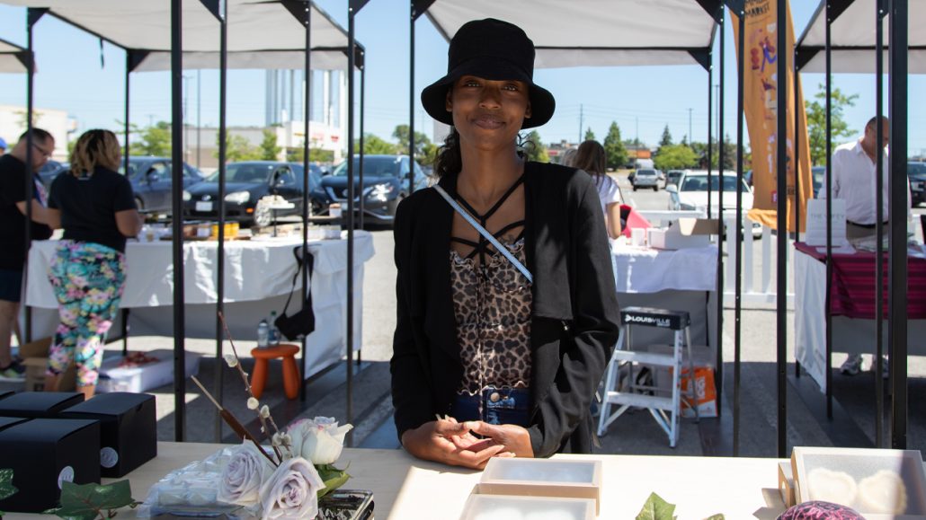 A merchant from the ILEO market poses behind her stand. 