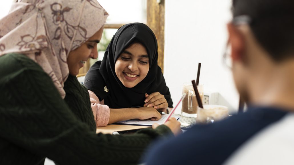 A woman and a young girl work on a writing assignment together. 