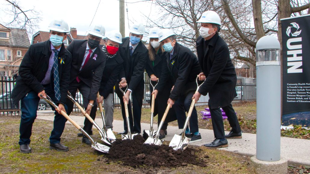 Representatives from the different organizations working on the Social Medicine Initiative post in hard hats with shovels at the construction site.