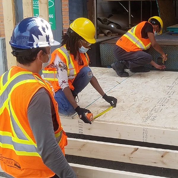 People working on a building wearing hard hats and vests.