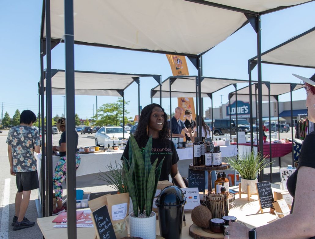 ILEO Storefront entrepreneur in booth selling products at the summer pop-up market.