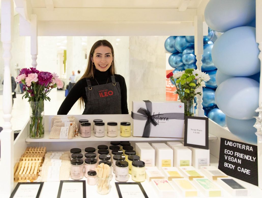 ILEO Storefront entrepreneur in booth selling products at the holiday pop-up market.