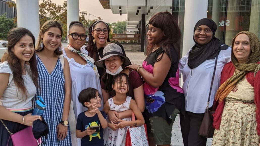 A group of women and two children from The Toronto Centre for Community Learning & Development pose on the sidewalk