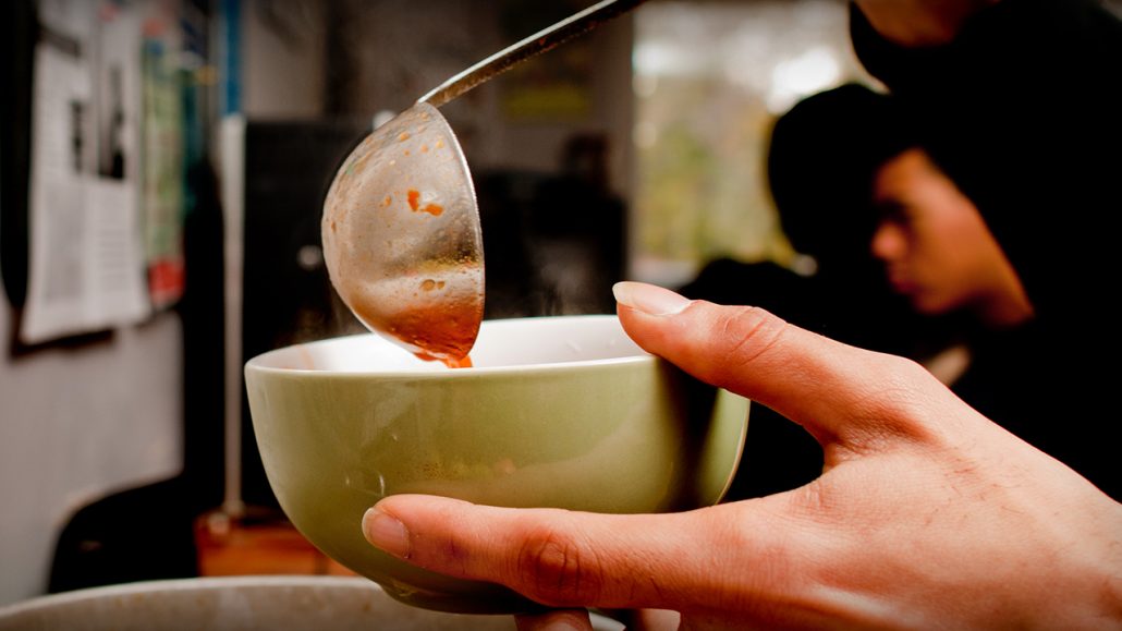 A person ladling soup into a bowl